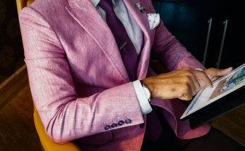 man wearing pink suit jacket holding using tablet computer